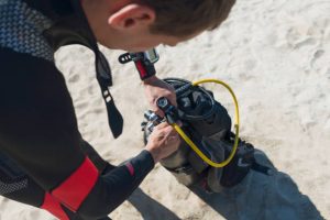 a scuba diver openning his tank valve