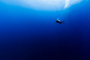 a scuba diver descending deeper underwater