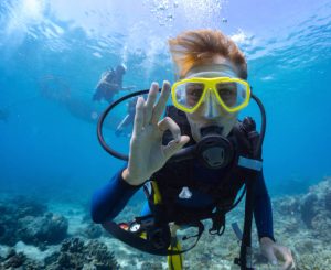 a scuba diver wearing his scuba regulator and giving his ok signal